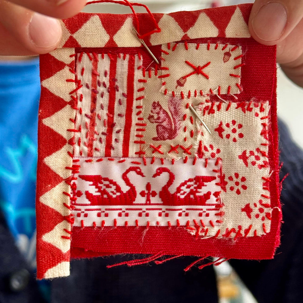 Red and white fabric patchwork held by a person with a blurred background