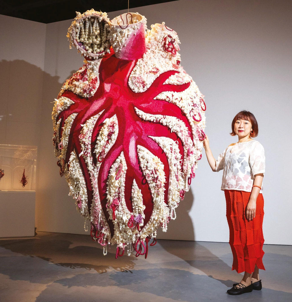 Person standing next to a large, intricate costume with red and white design