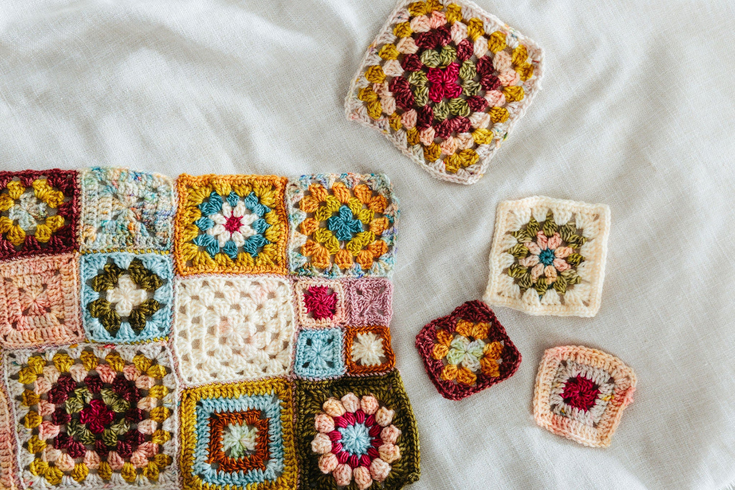 Collection of colorful crocheted squares on a white fabric background