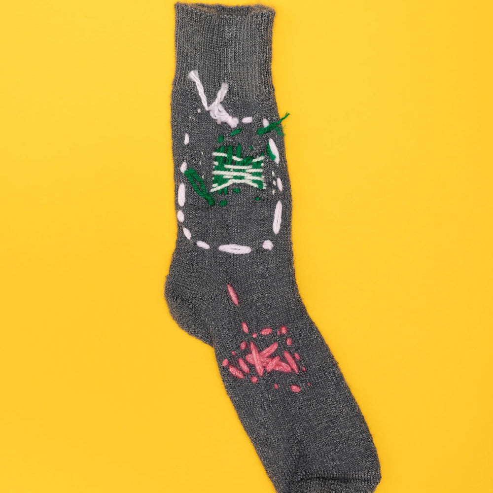 Gray sock with colorful designs on a yellow background