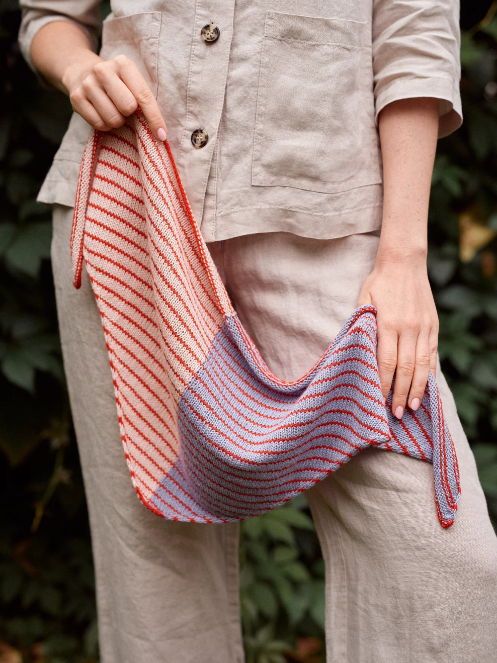 Person holding a striped knitted bag with a natural background