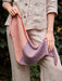 Person holding a striped knitted bag with a natural background