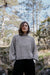 Person wearing a gray sweater in a forest setting