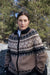 Woman wearing a patterned sweater outdoors with trees in the background