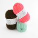 Three balls of yarn in pink, brown, and green on a white background