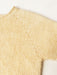 Close-up of a light beige or cream-colored knit garment, showing the fine knit texture and a decorative pointed lace or eyelet stitch detail along the neckline.