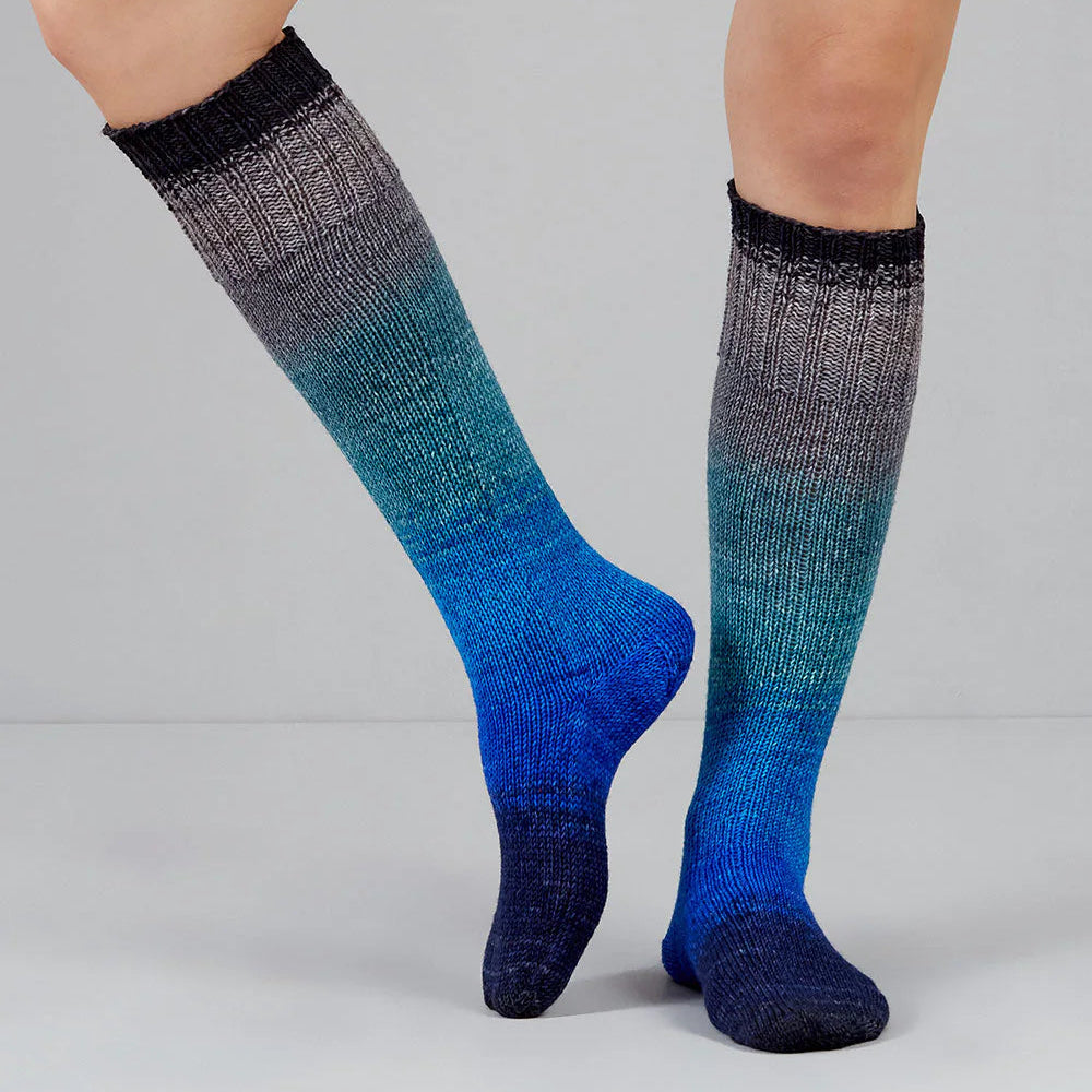 Blue and gray gradient socks worn by a person on a light gray background