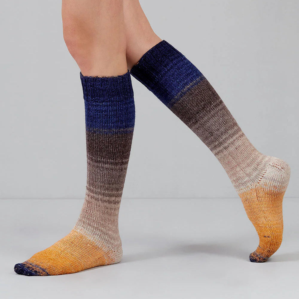 Colorful striped socks worn by a person on a plain background