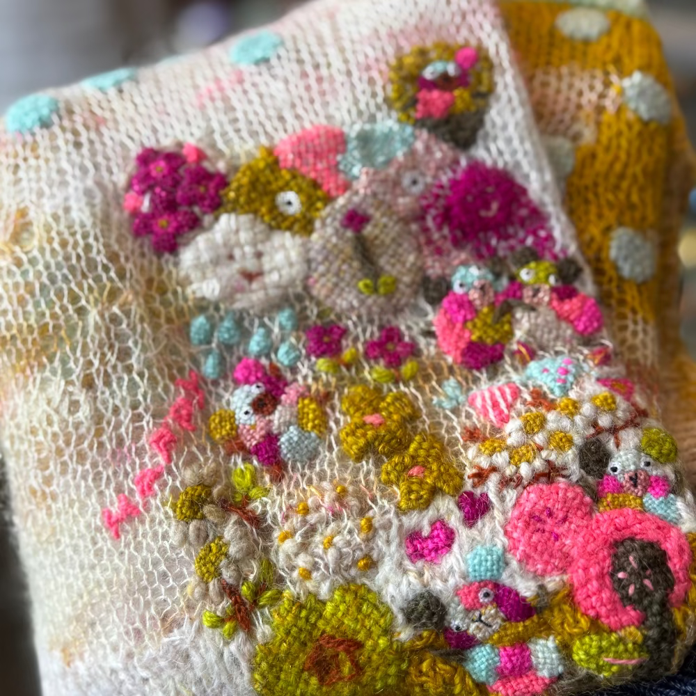 Embroidered fabric with colorful floral patterns and a cat design.
