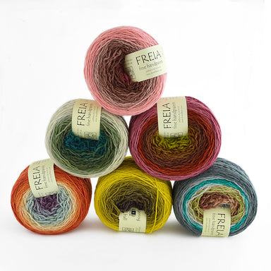 Colorful yarn balls stacked on a white background with Freia labels.