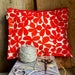 Red floral-patterned pouch with a ball of yarn and scissors on a wooden surface