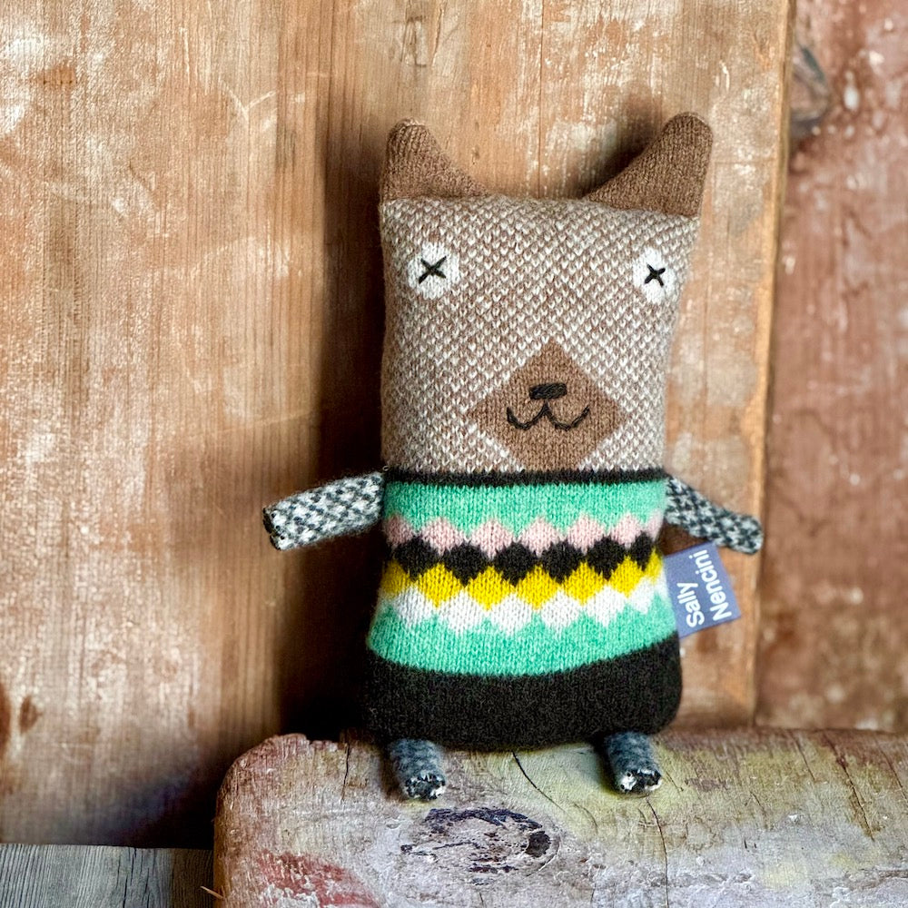 Knitted dog toy wearing a colorful sweater on a wooden background