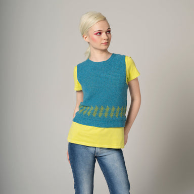 Woman wearing a blue and yellow sleeveless top with jeans on a gray background