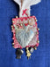 Decorative brooch with leaf design and various charms on a blue background