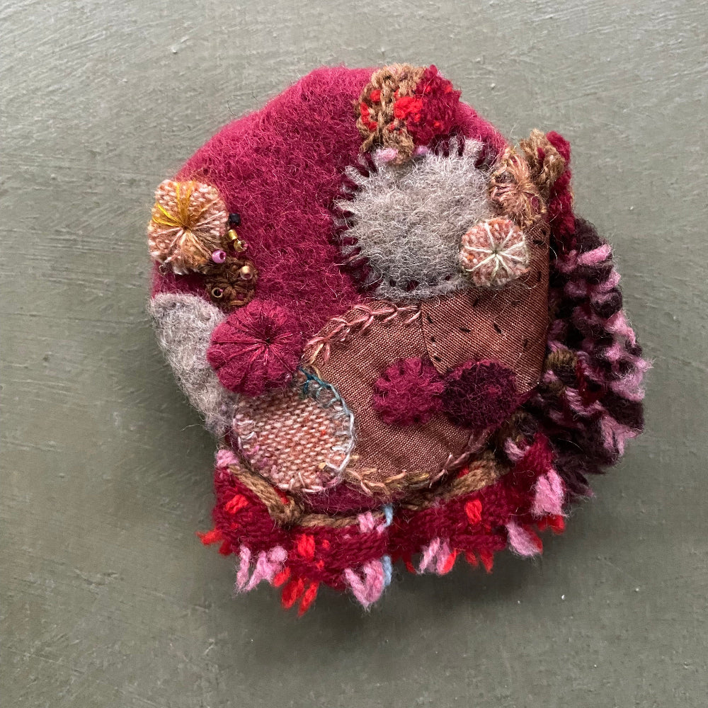 Textile art piece resembling a hedgehog on a gray background