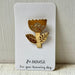 A gold metal flower-shaped pin with two leaves and a textured center, mounted on a white display card printed with the brand name '80.HOUSE' and the phrase 'For your humming day.