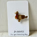 A small duck-shaped brooch in a textured gold-tone metal with a subtle red accent on the body, mounted on a white display card that reads '80.HOUSE For your humming day.