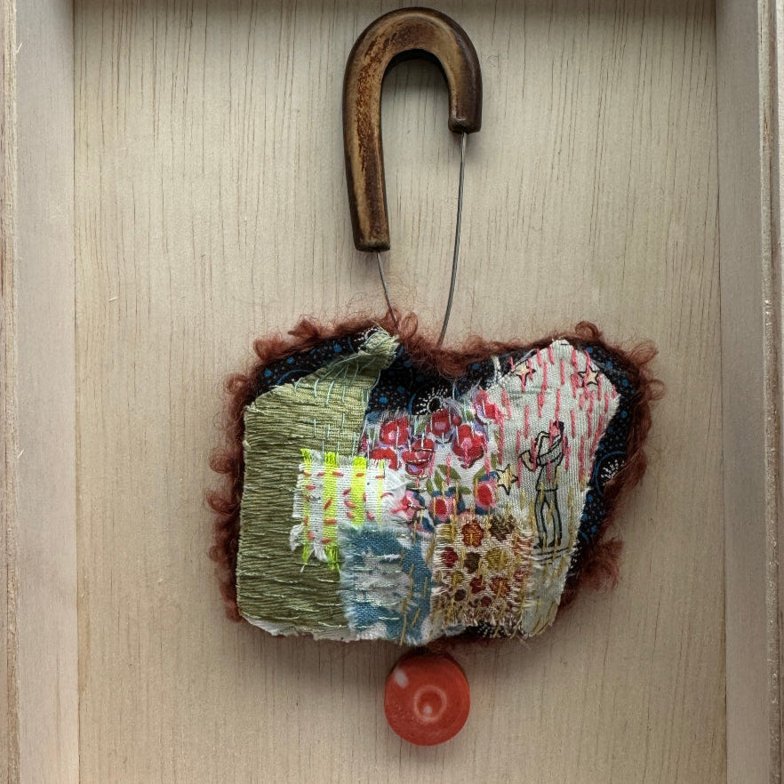 Textile art piece with a horseshoe on a wooden background