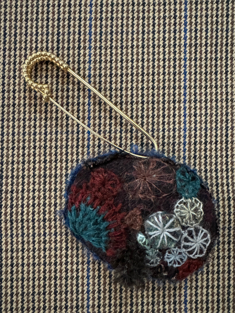 Decorative brooch with floral patterns on a textured fabric background