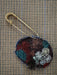 Decorative brooch with floral patterns on a textured fabric background
