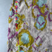 Colorful floral patterned fabric with tassels on a gray background