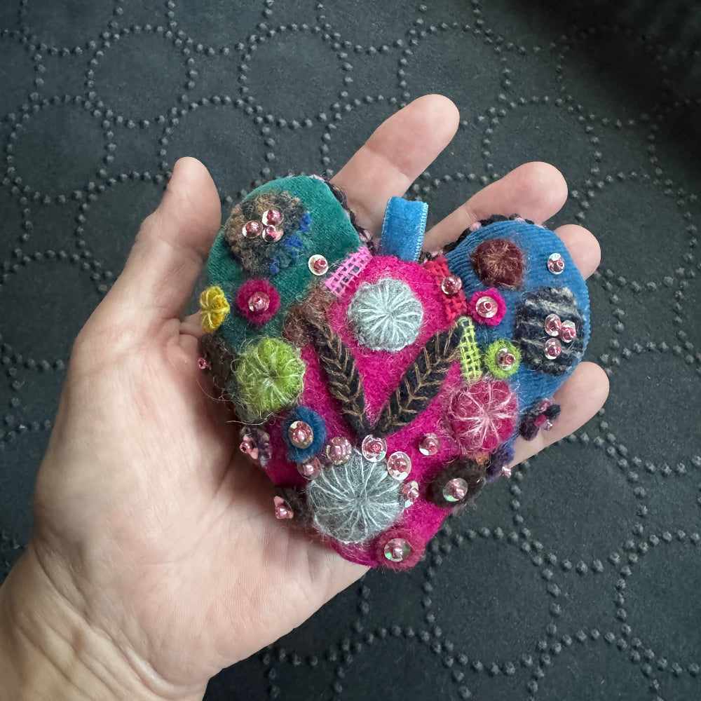 Colorful embroidered fabric piece held in a hand against a textured black background