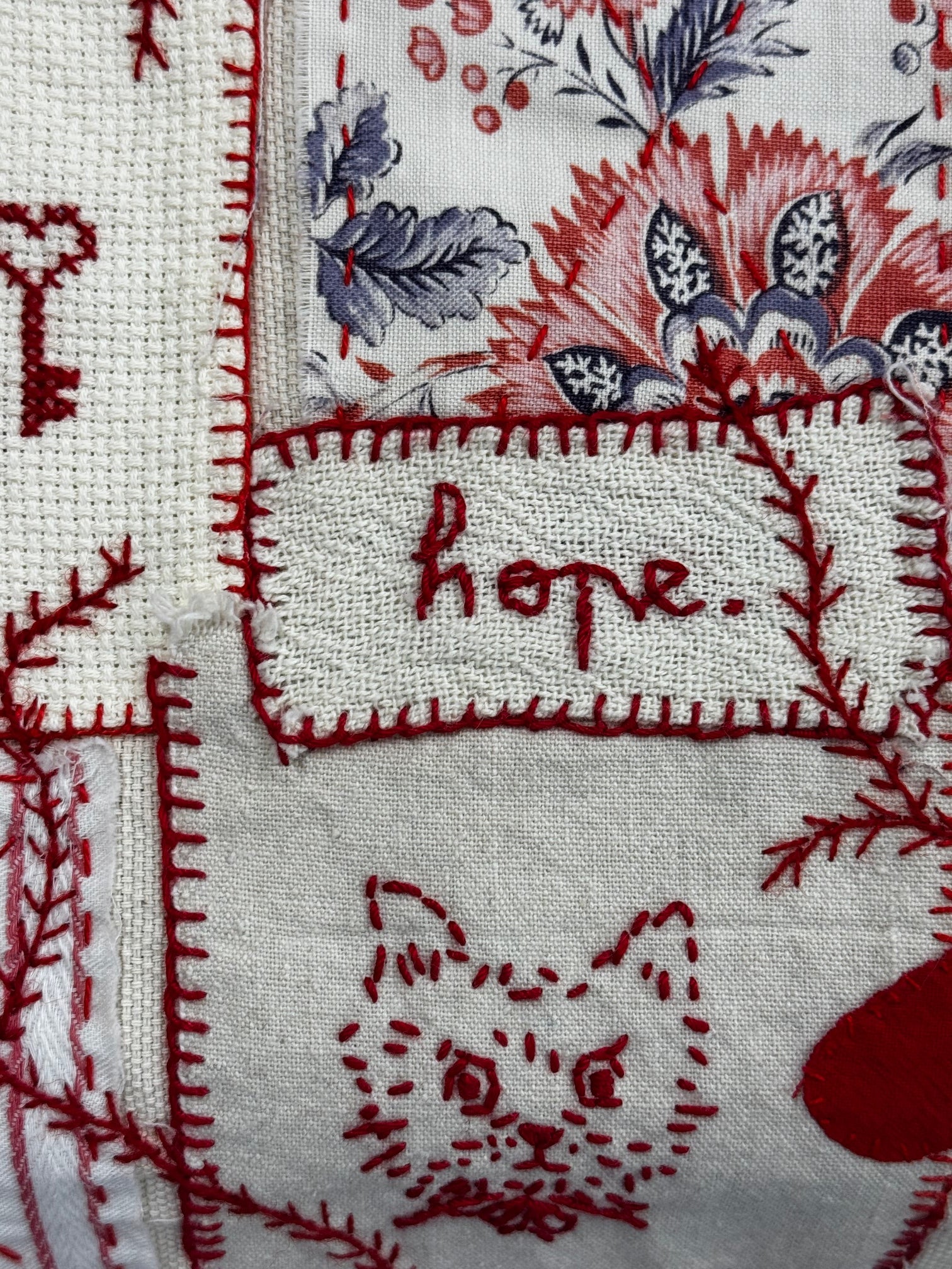 Embroidered fabric with floral patterns and the word 'Hope' in red thread.