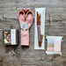 Set of pink scissors, knife, and thread on a wooden surface with Cohana branding.