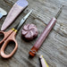 Scissors, crochet hook, and other tools on a wooden surface