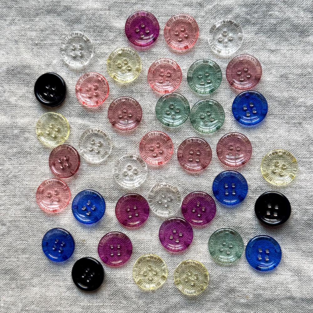 Assorted colorful buttons on a gray fabric background