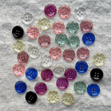 Assorted colorful buttons on a gray fabric background