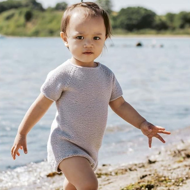 Child in a Romper standing on a beach 