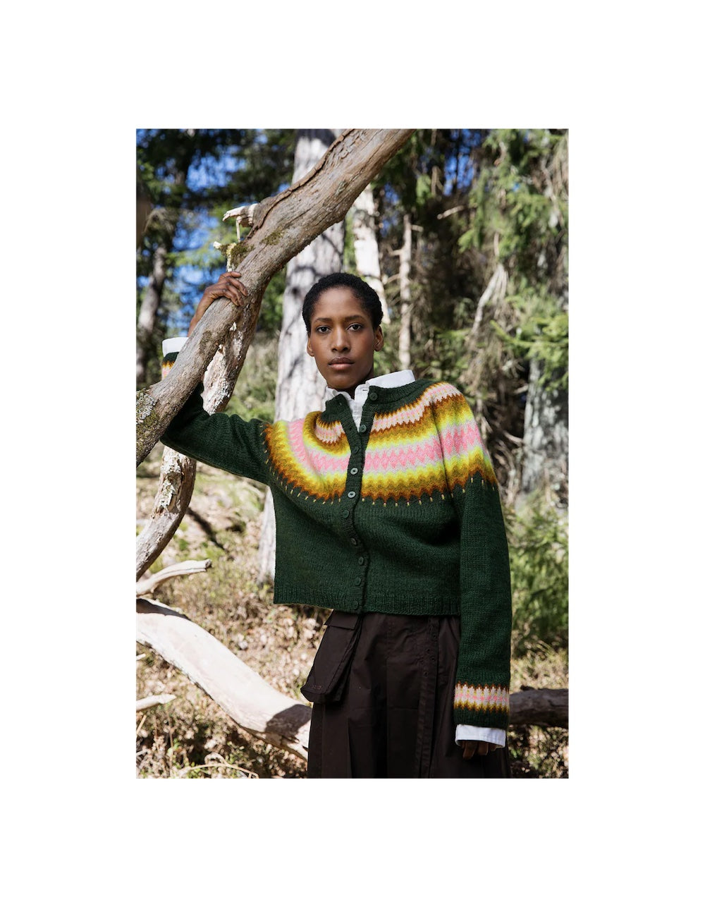Person wearing a green sweater with a colorful pattern in a forest setting