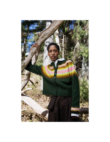 Person wearing a green sweater with a colorful pattern in a forest setting