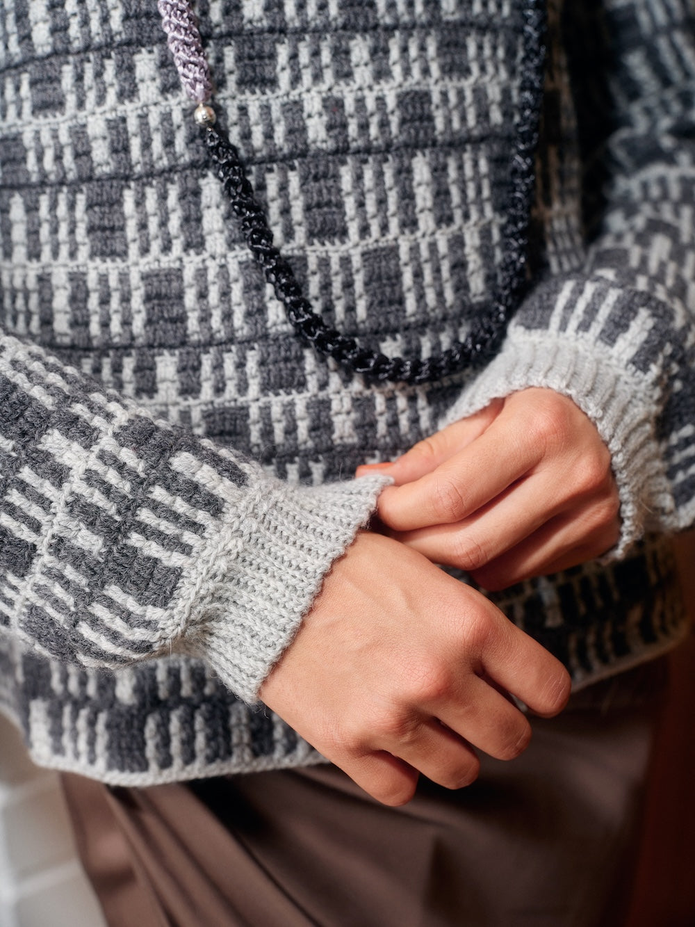 Close-up of a person wearing a patterned sweater with a focus on the sleeve and hands.