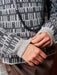 Close-up of a person wearing a patterned sweater with a focus on the sleeve and hands.