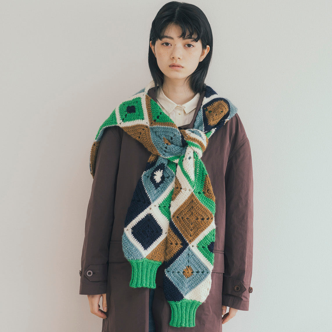 Person wearing a colorful geometric-patterned scarf with a plain background