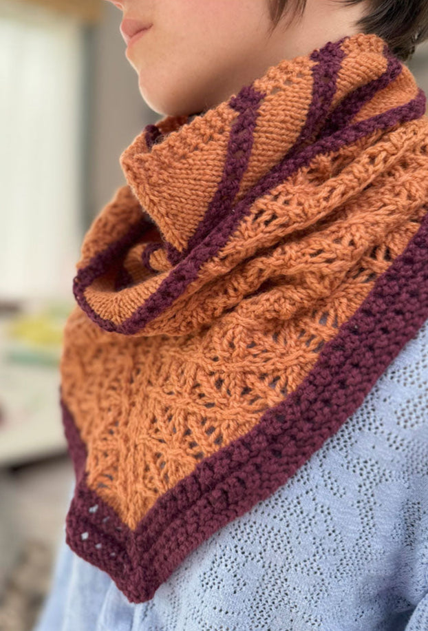 Person wearing a knitted scarf with orange and purple pattern