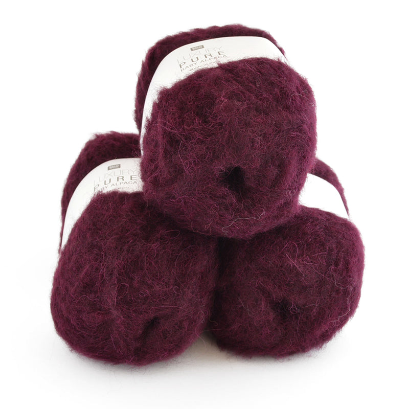 Three skeins of dark red yarn stacked on a white background