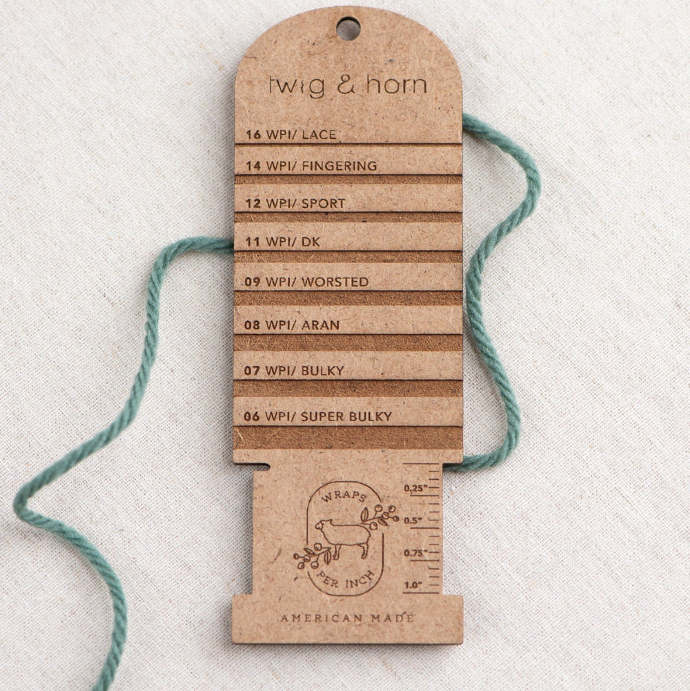 Wooden yarn weight gauge with measurements on a textured white background