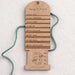 Wooden yarn weight gauge with measurements on a textured white background