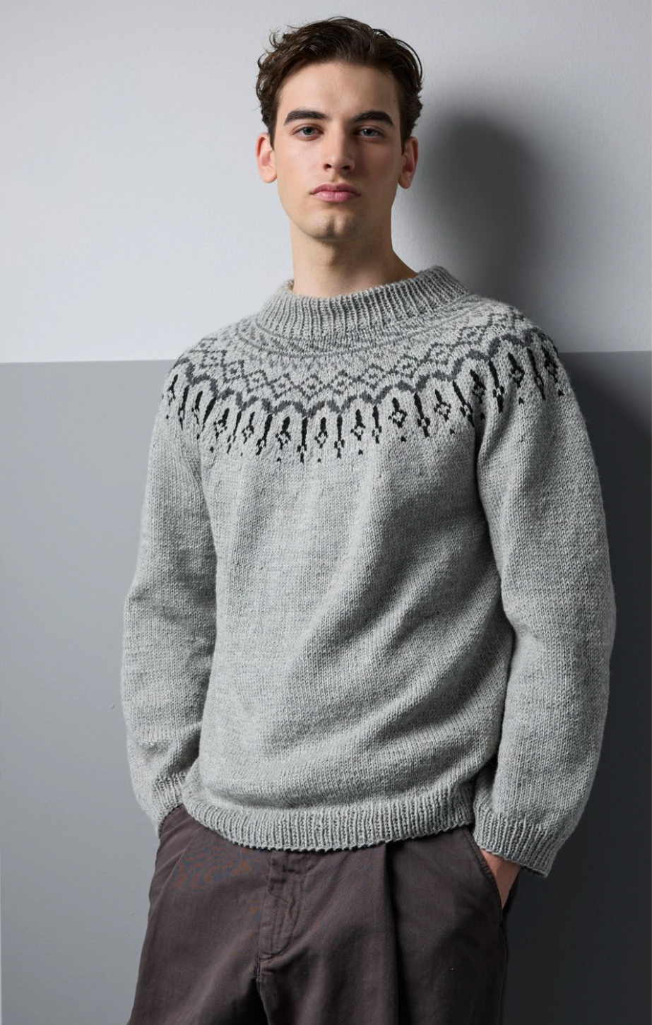 Man wearing a gray sweater with intricate pattern against a plain background