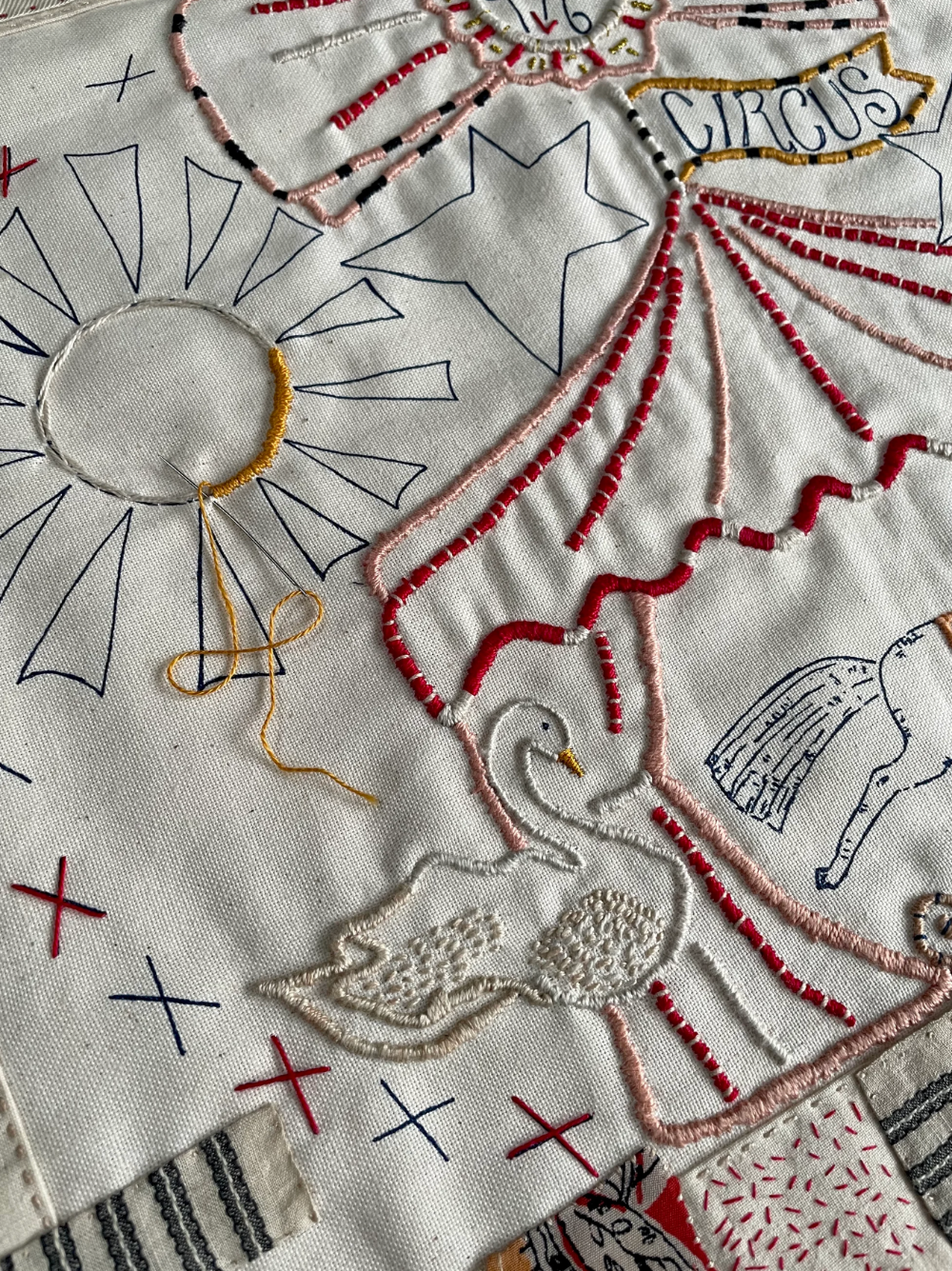 Embroidered design on fabric with circus-themed elements including a balloon, umbrella, and star.