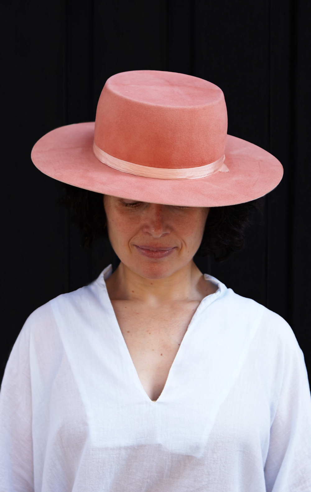 Person wearing a pink hat against a black background