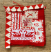 Red and white embroidered fabric square on a wooden surface