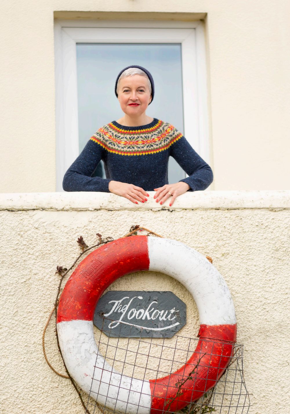 Woman in a window with a life buoy and 'The Lookout' sign below.