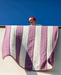 Person holding a striped knitted blanket against a blue sky