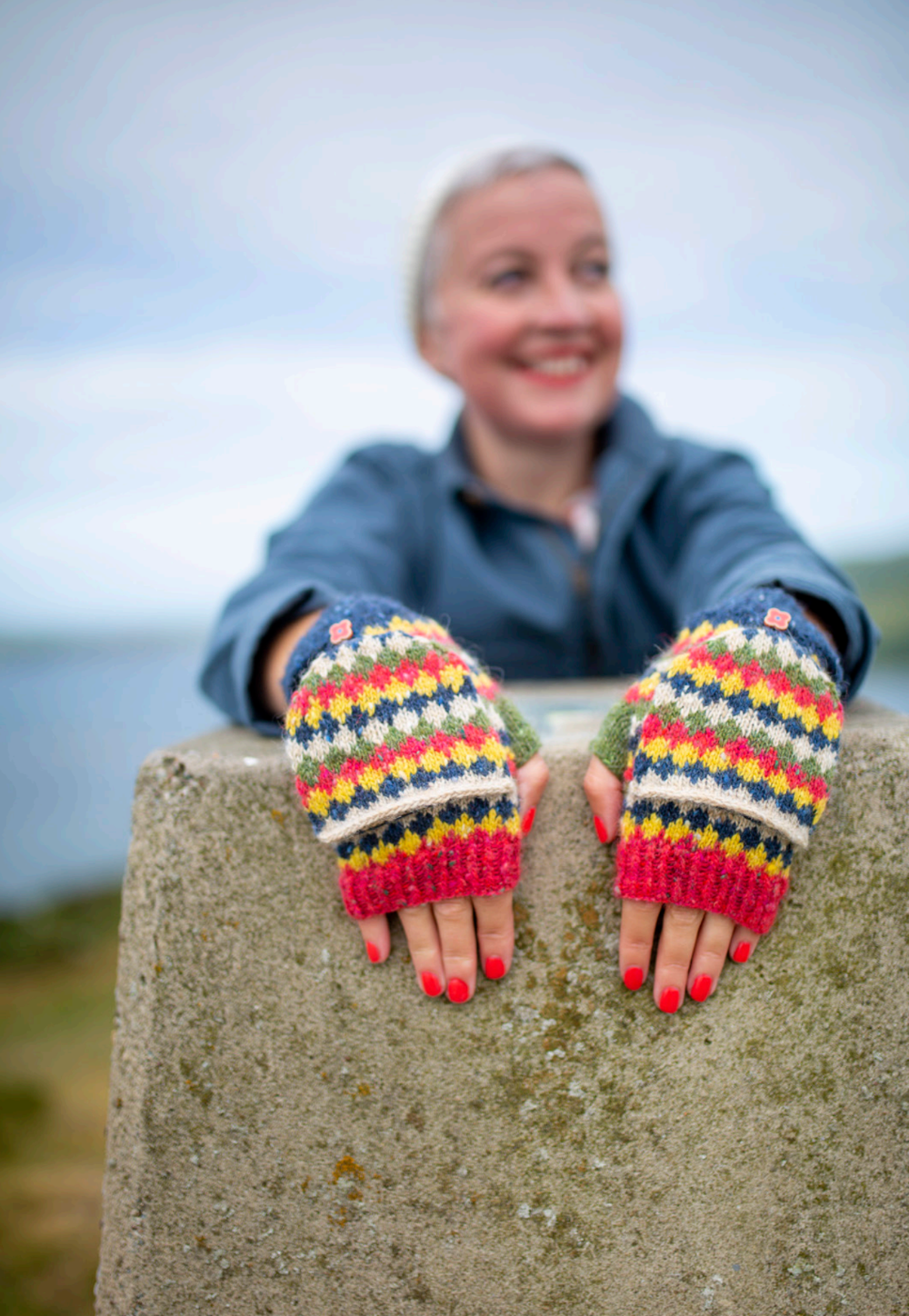 Person wearing colorful knitted gloves outdoors