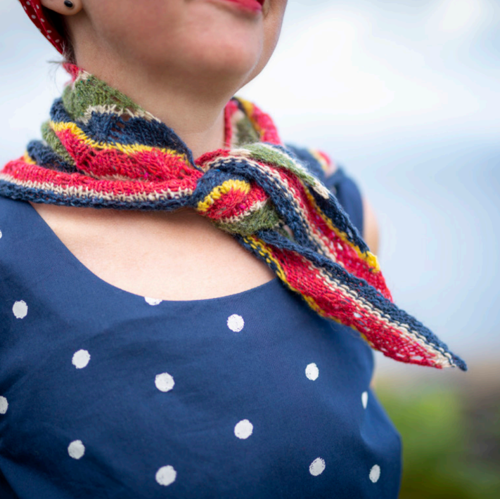 Person wearing a colorful knitted scarf with a blurred background