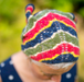 Colorful knitted hat worn by a woman with a blurred natural background